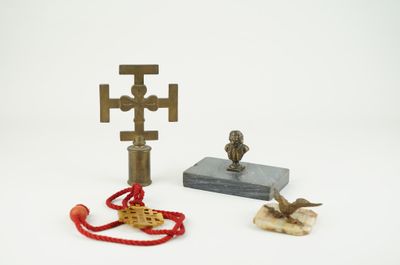 une petite statue représentant un oiseau et une croix, à côté d'une autre petite statue représentant un oiseau et une croix