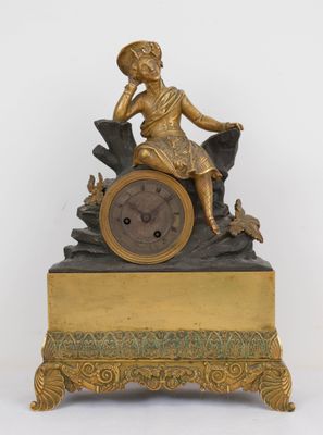 a gold clock with a woman sitting on top of it