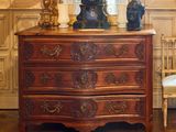 une commode sur laquelle est posée une horloge, dans une pièce