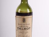 an old bottle of wine sitting on top of a white table