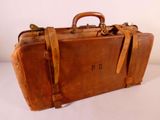 une valise en cuir marron posée sur une surface blanche