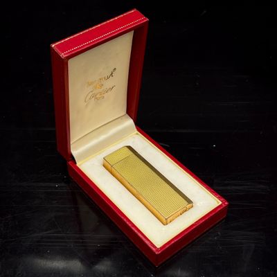 un briquet doré dans une boîte rouge posée sur une table noire