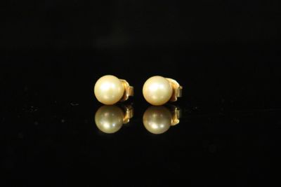 a pair of pearl earrings on a black surface