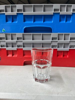 un verre d'eau posé sur un plan de travail à côté d'un récipient en plastique
