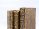 two old books sitting on top of each other on a white surface