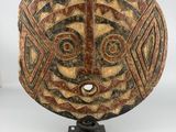 a wooden mask on a stand with a white background