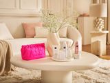 une table basse blanche sur laquelle est posé un sac rose