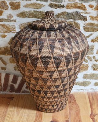 une photo d'un vase tressé posé sur une table en bois
