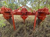a close up of a red tractor plow in a field