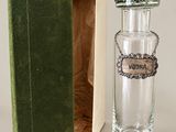 a small glass bottle with a silver lid in a green box