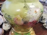 a vase on a table with a lot of cups and saucers on it