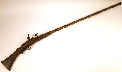 un vieux fusil avec une poignée en bois sur une surface blanche