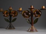 pair of metal candelabs with flowers and leaves on them