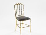 an image of a gold chair with black leather seat on a white background