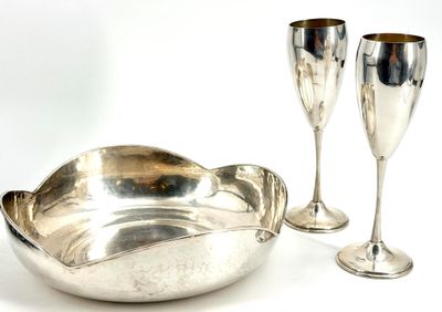 deux verres à vin et un bol en argent posés sur une table