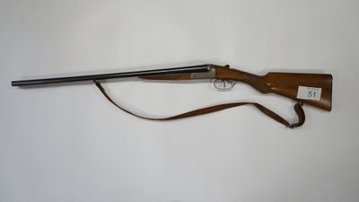 the rifle is laying on a white surface with a brown strap