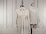 two white shirts on a mannequin stand in front of a white wall