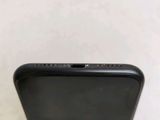the back of a black iphone with a small hole in the middle of it