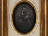 an old picture of a man in a suit and tie holding a pipe