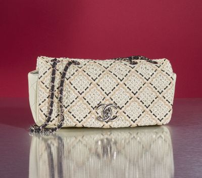 beige and black handbag with chain strap on a shiny surface