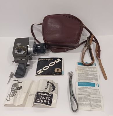 a brown bag, a camera, a book and other items laid out on a table