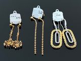 three pairs of gold and silver earrings on a black surface