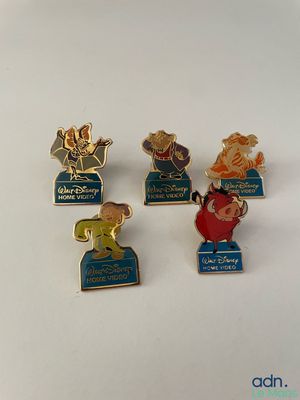 four disney pin badges are sitting on a white surface