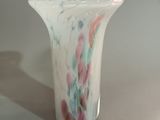 un vase blanc orné d'un motif multicolore posé sur une table