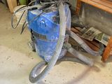 un aspirateur bleu posé par terre dans une pièce