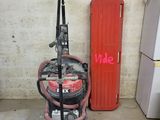 un aspirateur rouge et noir et un réfrigérateur rouge dans une pièce