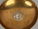 a close up of a gold plate with a medallion on it