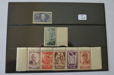 plusieurs timbres différents sur un dossier noir, avec une personne tenant l'un d'entre eux