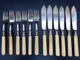 six fourchettes et cinq couteaux sont alignés sur une table