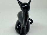 a black cat figurine sitting on a white surface