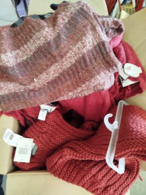 une boîte remplie de pulls et un bonnet posés sur une table
