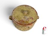 a small pot with a lid sitting on a white surface