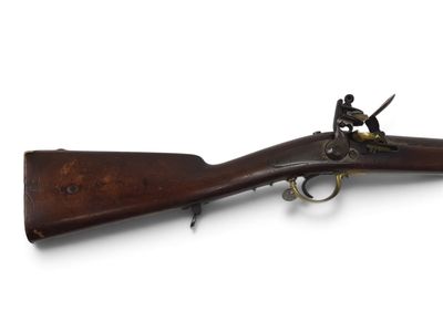 un vieux fusil exposé sur une surface blanche