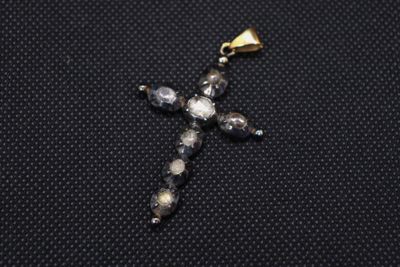 a close up of a cross made of glass beads on a black surface