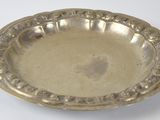 un plat en argent ancien posé sur une table blanche, sur fond blanc