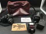 un appareil photo, un flash, un étui pour appareil photo, une lampe de poche et d'autres objets posés sur une table