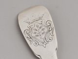 a silver spoon with a design on it sitting on a table