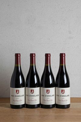four bottles of red wine lined up on a wooden table