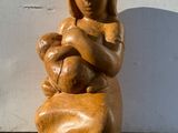 une statue en bois représentant une femme tenant un bébé dans ses bras
