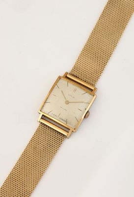 gros plan d'une montre en or sur une surface blanche