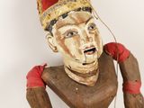 une statue en bois représentant un homme coiffé d'un chapeau
