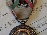 une médaille sur laquelle figure le portrait d'un homme, posée sur une partition