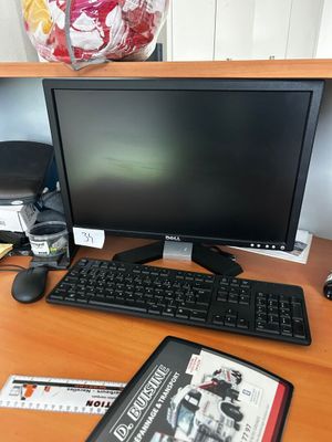 un écran d'ordinateur, un clavier, une souris et un magazine posés sur le bureau