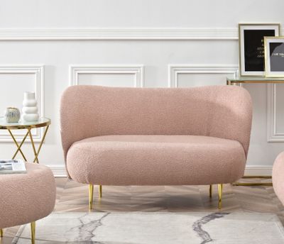 Le salon est équipé d'un canapé, d'un fauteuil et d'un pouf roses.