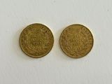 two gold coins sitting side by side on a white surface