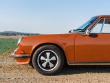 an orange car parked on the side of a dirt road